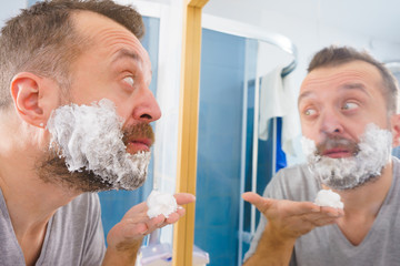 Guy shaving his beard in bathroom