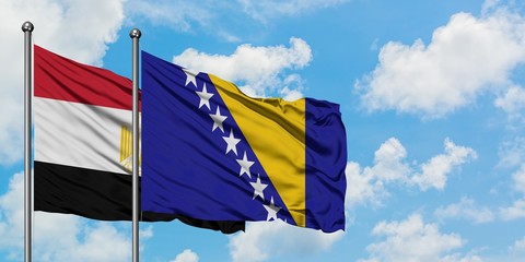 Egypt and Bosnia Herzegovina flag waving in the wind against white cloudy blue sky together. Diplomacy concept, international relations.