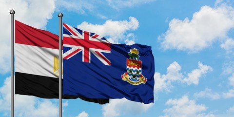 Egypt and Cayman Islands flag waving in the wind against white cloudy blue sky together. Diplomacy concept, international relations.