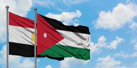 Egypt and Jordan flag waving in the wind against white cloudy blue sky together. Diplomacy concept, international relations.