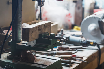 Old vertical drilling machine on the table in the workshop. Close-up.