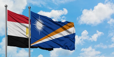 Egypt and Marshall Islands flag waving in the wind against white cloudy blue sky together....