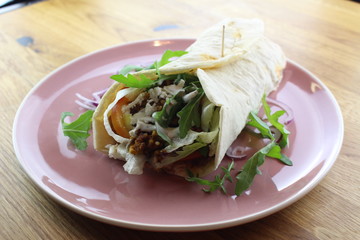 Delicious beef burrito with salad and cheese on a white plate.