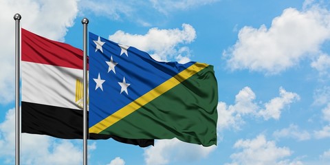 Egypt and Solomon Islands flag waving in the wind against white cloudy blue sky together. Diplomacy concept, international relations.