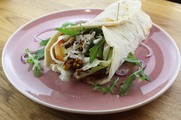Delicious beef burrito with salad and cheese on a white plate.