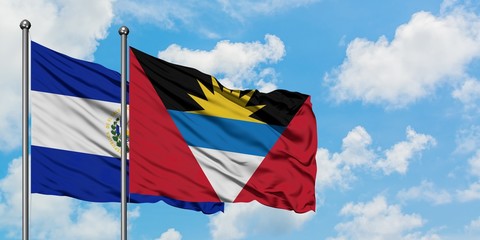 El Salvador and Antigua and Barbuda flag waving in the wind against white cloudy blue sky together. Diplomacy concept, international relations.