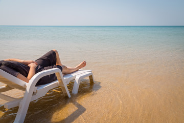 Vacation on tropical beach Woman's legs on the beach bed with clear ocean water