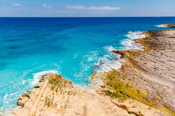 Fototapeta na wymiar Blue emerald sea water with large stones beach. Rocky shore transparent turquoise bottom Malta
