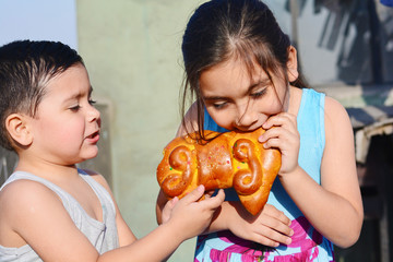 Latin kids eating tantawawa - typical sweet bread for All Saints Day.