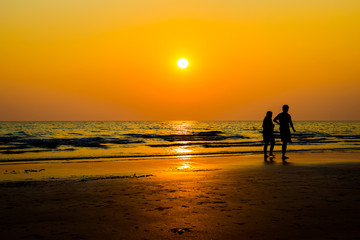 Siluate lovers and beach before sunset