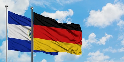 El Salvador and Germany flag waving in the wind against white cloudy blue sky together. Diplomacy concept, international relations.