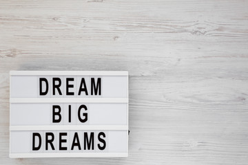 'Dream big dreams' words on a modern board on a white wooden surface, top view. Overhead, from above, flat lay. Space for text.