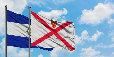 El Salvador and Jersey flag waving in the wind against white cloudy blue sky together. Diplomacy concept, international relations.