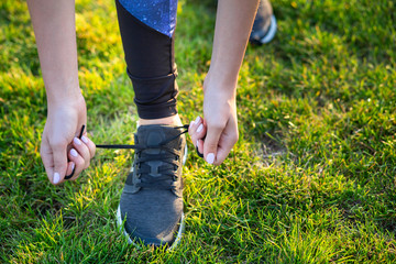 Close-up of female hands tying shoelace on running shoes before practice. Runner getting ready for...