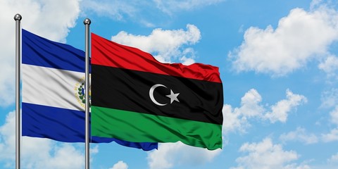 El Salvador and Libya flag waving in the wind against white cloudy blue sky together. Diplomacy...