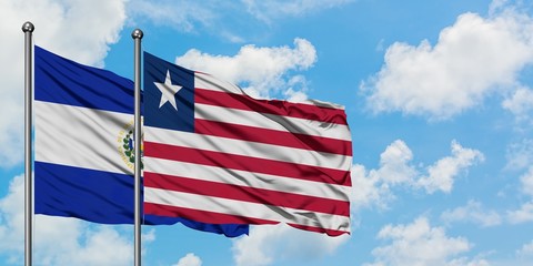 El Salvador and Liberia flag waving in the wind against white cloudy blue sky together. Diplomacy concept, international relations.