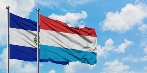 El Salvador and Luxembourg flag waving in the wind against white cloudy blue sky together. Diplomacy concept, international relations.