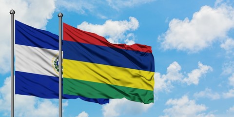 El Salvador and Mauritius flag waving in the wind against white cloudy blue sky together. Diplomacy concept, international relations.