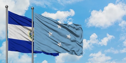 El Salvador and Micronesia flag waving in the wind against white cloudy blue sky together....