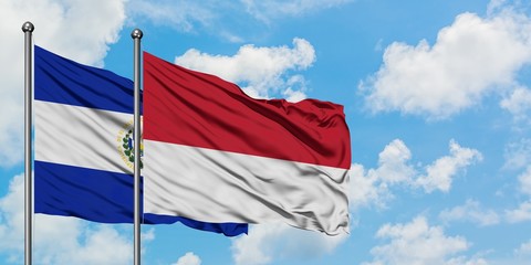 El Salvador and Monaco flag waving in the wind against white cloudy blue sky together. Diplomacy concept, international relations.