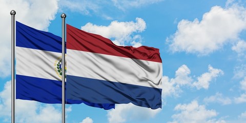 El Salvador and Netherlands flag waving in the wind against white cloudy blue sky together. Diplomacy concept, international relations.