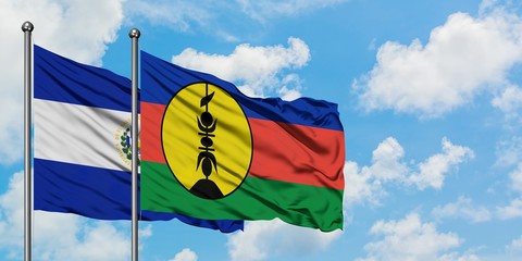 El Salvador and New Caledonia flag waving in the wind against white cloudy blue sky together....