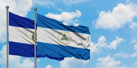 El Salvador and Nicaragua flag waving in the wind against white cloudy blue sky together. Diplomacy concept, international relations.
