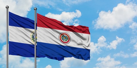 El Salvador and Paraguay flag waving in the wind against white cloudy blue sky together. Diplomacy concept, international relations.