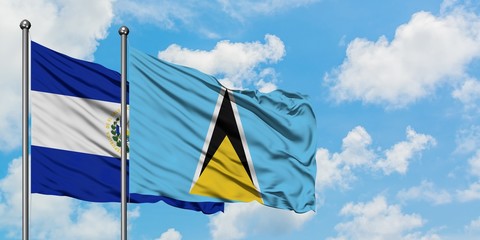 El Salvador and Saint Lucia flag waving in the wind against white cloudy blue sky together. Diplomacy concept, international relations.