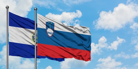 El Salvador and Slovenia flag waving in the wind against white cloudy blue sky together. Diplomacy concept, international relations.