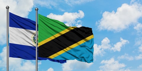 El Salvador and Tanzania flag waving in the wind against white cloudy blue sky together. Diplomacy concept, international relations.