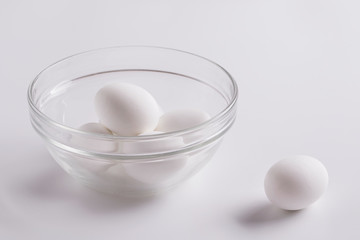 Still life of white raw eggs. Eggs on the kitchen table. White raw eggs in a glass plate on a white background.