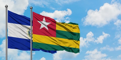 El Salvador and Togo flag waving in the wind against white cloudy blue sky together. Diplomacy concept, international relations.