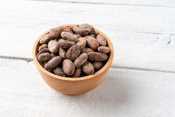 Cocoa beans in bowl on vintage wooden table