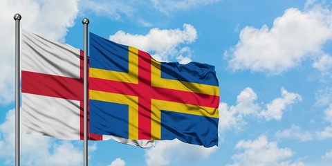 England and Aland Islands flag waving in the wind against white cloudy blue sky together. Diplomacy concept, international relations.