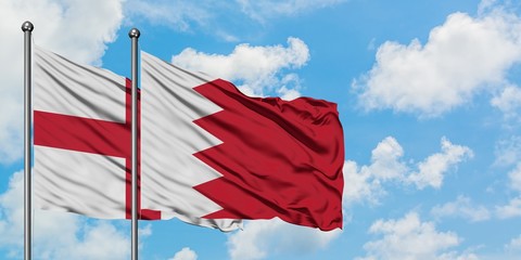 England and Bahrain flag waving in the wind against white cloudy blue sky together. Diplomacy...