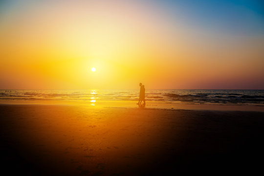 Siluate lovers and beach before sunset