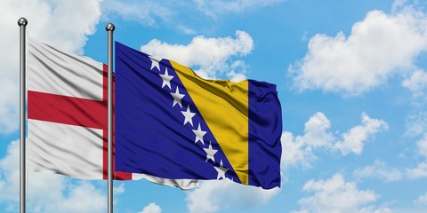 England and Bosnia Herzegovina flag waving in the wind against white cloudy blue sky together. Diplomacy concept, international relations.