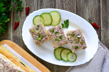 Layer cake with eggs, cheese, green onions, canned fish, mayonnaise on a white plate on a wooden table. Festive appetizer. Top view.