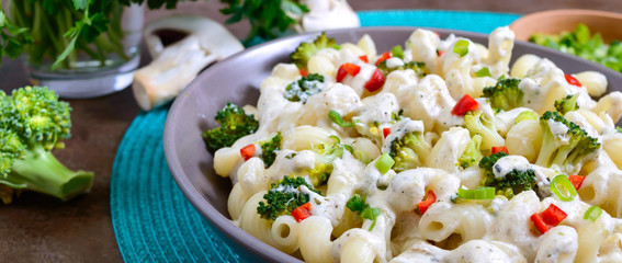 Cavatappi pasta with broccoli, red pepper and cream sauce in a bowl. Vegetarian dish. Delicious healthy food. Proper nutrition. Banner