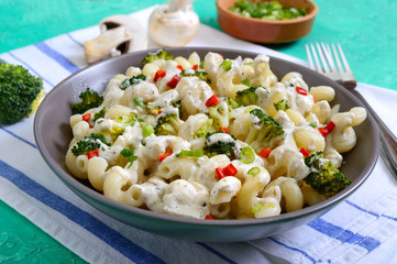 Cavatappi pasta with broccoli, red pepper and cream sauce in a bowl. Vegetarian dish. Delicious wholesome food. Proper nutrition.