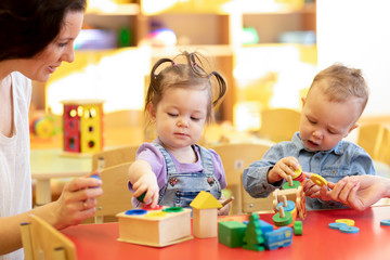 Children play with a teacher in nursery or kindergarten