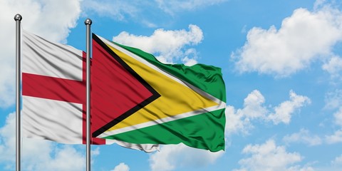 England and Guyana flag waving in the wind against white cloudy blue sky together. Diplomacy...
