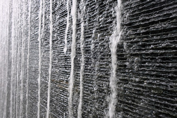 Black and gray stone walls are installed in the outdoor with water falling wave through from high to low has a bubble spread in the air, giving the feeling of cool, comfort, good sound like in nature.