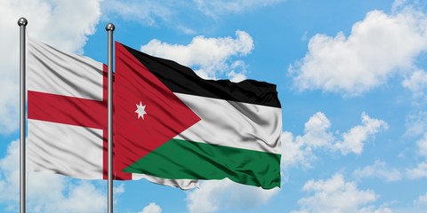 England and Jordan flag waving in the wind against white cloudy blue sky together. Diplomacy...