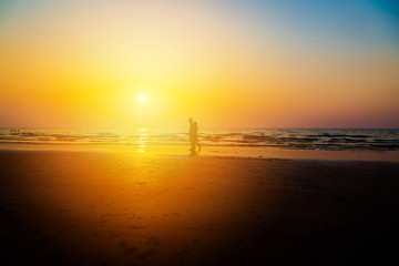 Siluate lovers and beach before sunset