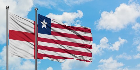 England and Liberia flag waving in the wind against white cloudy blue sky together. Diplomacy concept, international relations.