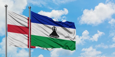 England and Lesotho flag waving in the wind against white cloudy blue sky together. Diplomacy...