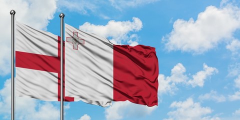 England and Malta flag waving in the wind against white cloudy blue sky together. Diplomacy concept, international relations.
