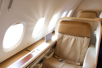 Business or first class seat of the airline have brown color near windows with sun light.They feel luxury , comfort and private when travel or work.Jet airplane and commercial are use for transport.